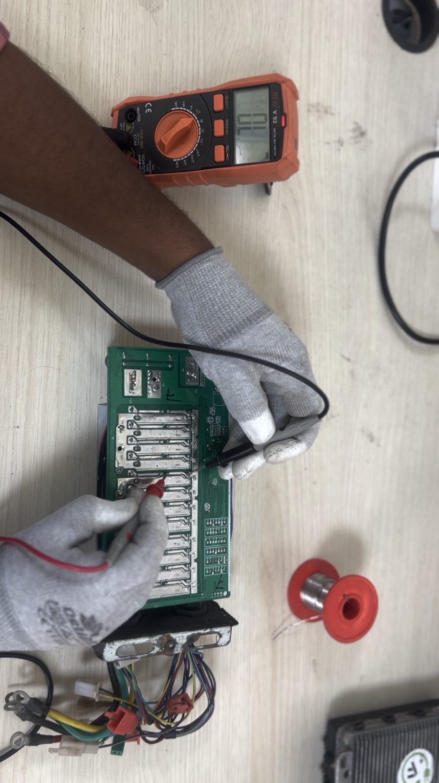 Technician testing and soldering a battery management system (BMS) board
