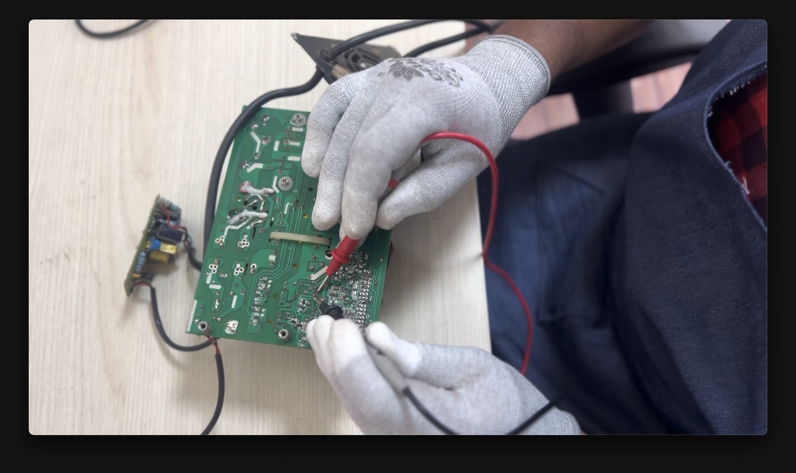 Technician testing a motor-controller PCB with a multimeter