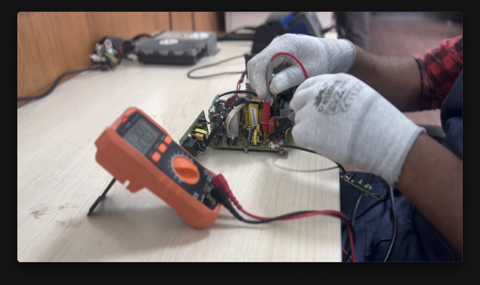Technician testing an EV charger controller PCB with a multimeter